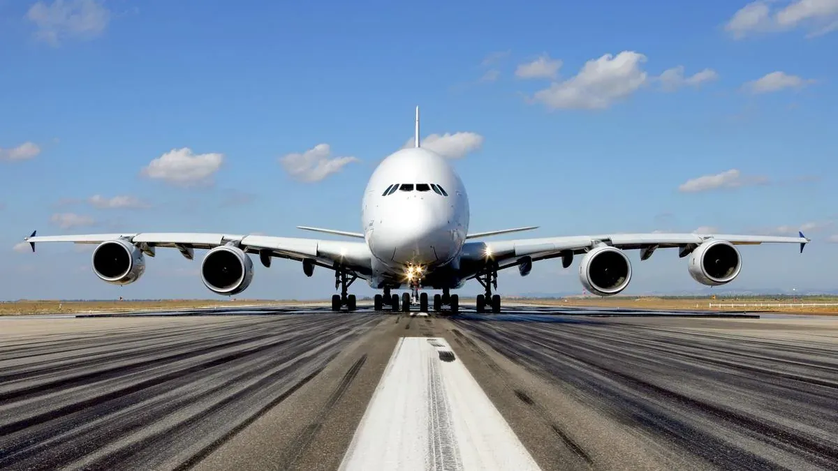 An Airbus A380 head-on on the runway, its four engines and double deck filling the frame.