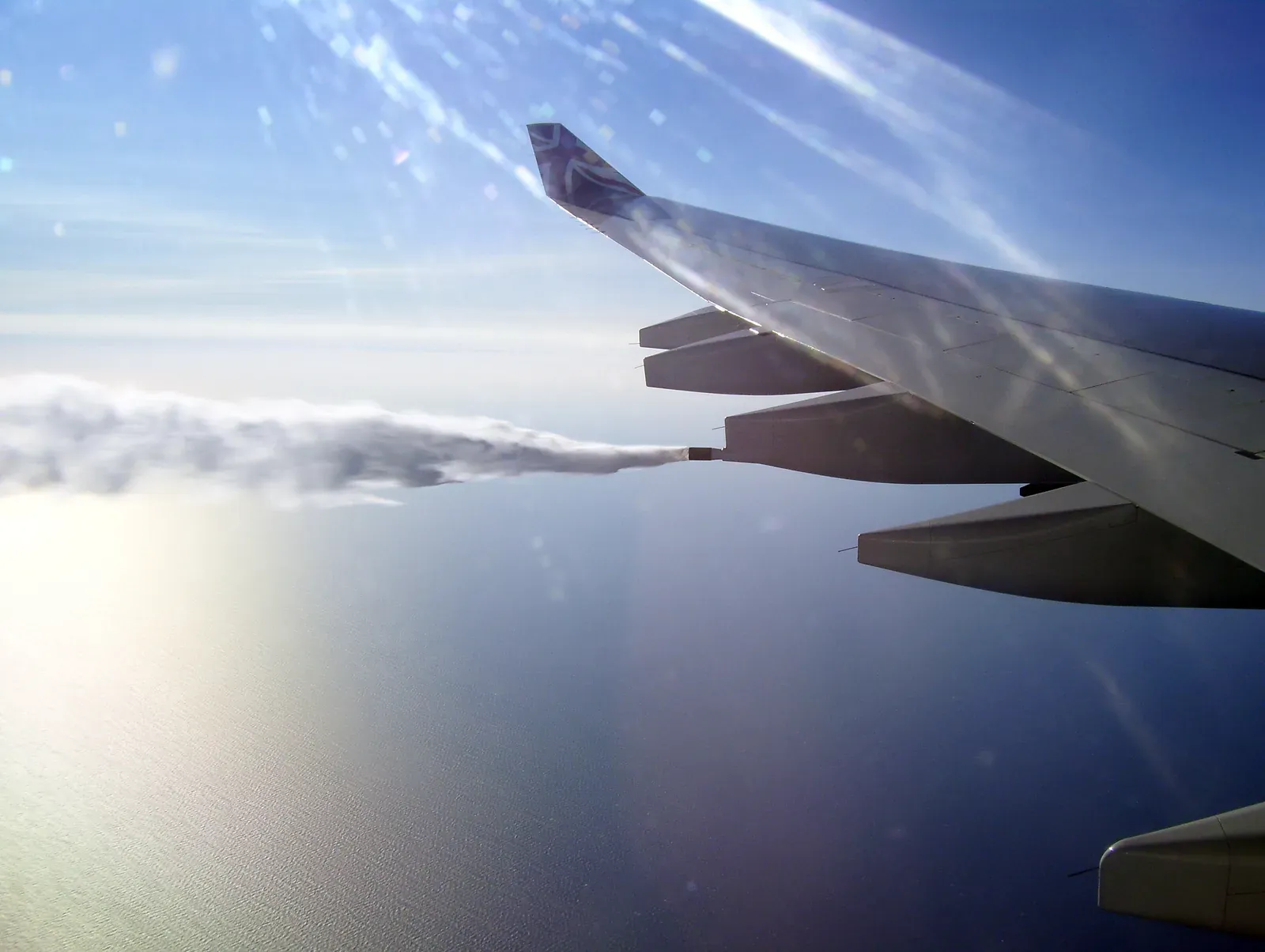 Fuel streaming from an airliner's wing at altitude, seen from a passenger window.