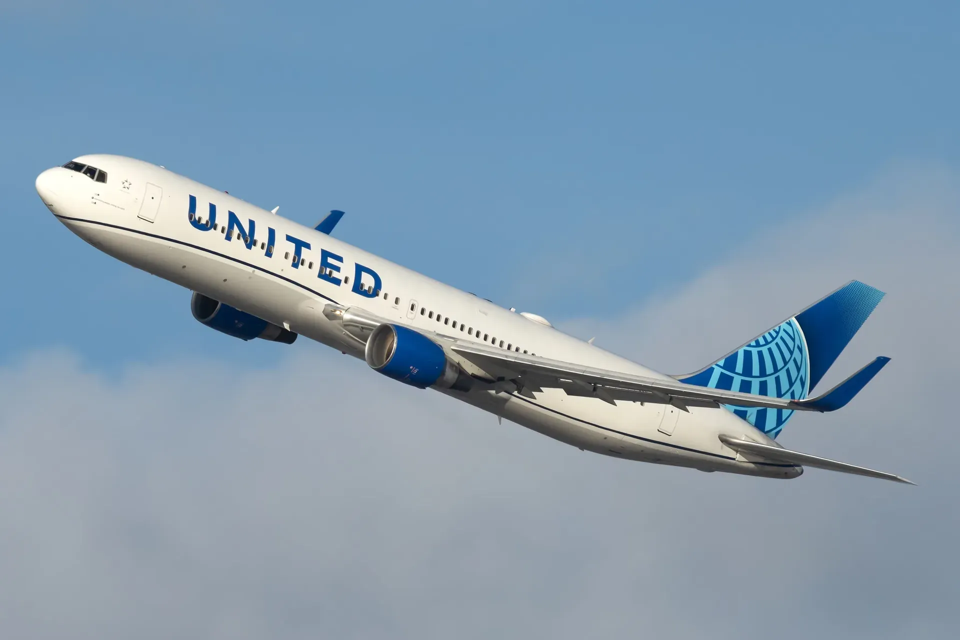 A United Airlines Boeing 767 climbing after takeoff against a pale sky
