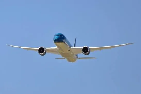 A twin-engine airliner seen head-on against a blue sky.