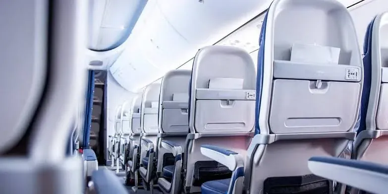 Rows of empty seats in an airliner cabin, receding down the aisle.